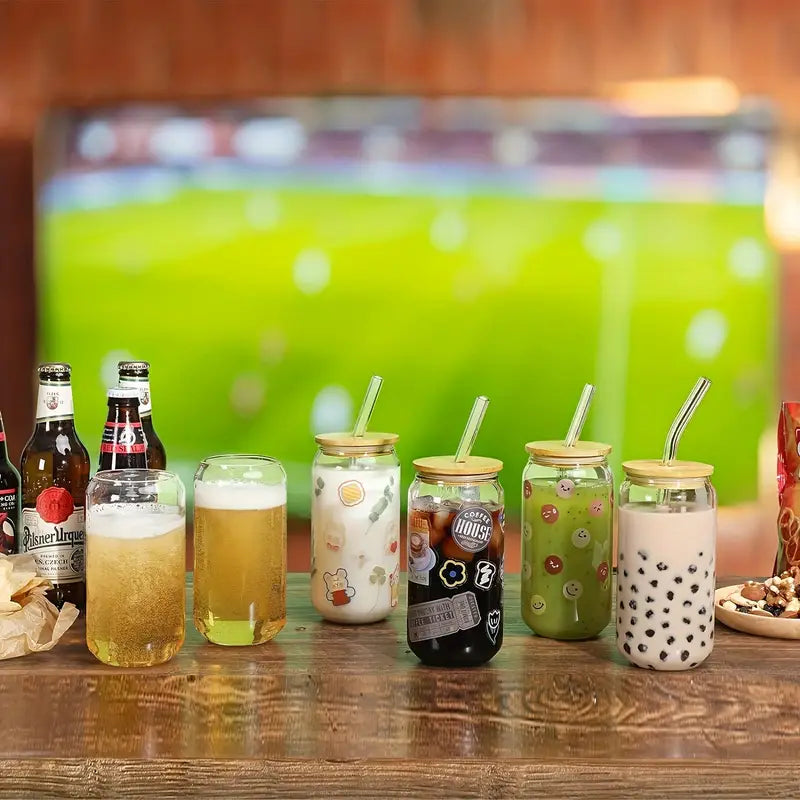 Vários copos de vidro com tampa de bambu enfileirados, servindo drinks em um evento com campo de futebol ao fundo.