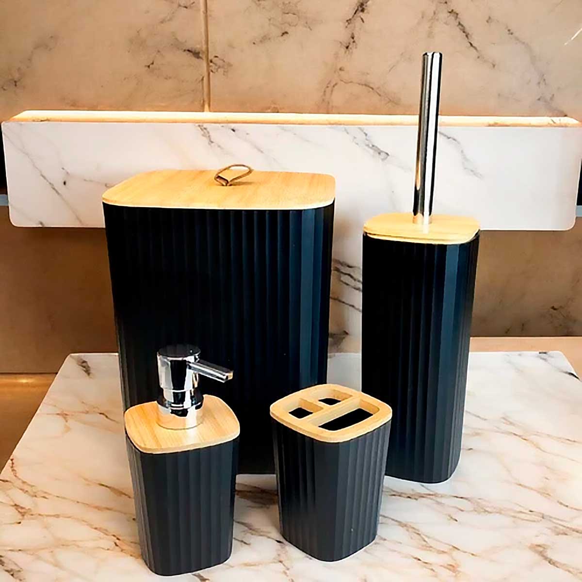 Kit de acessórios para banheiro de 4 peças na cor preta com detalhes em bambu, sobre uma bancada de mármore.