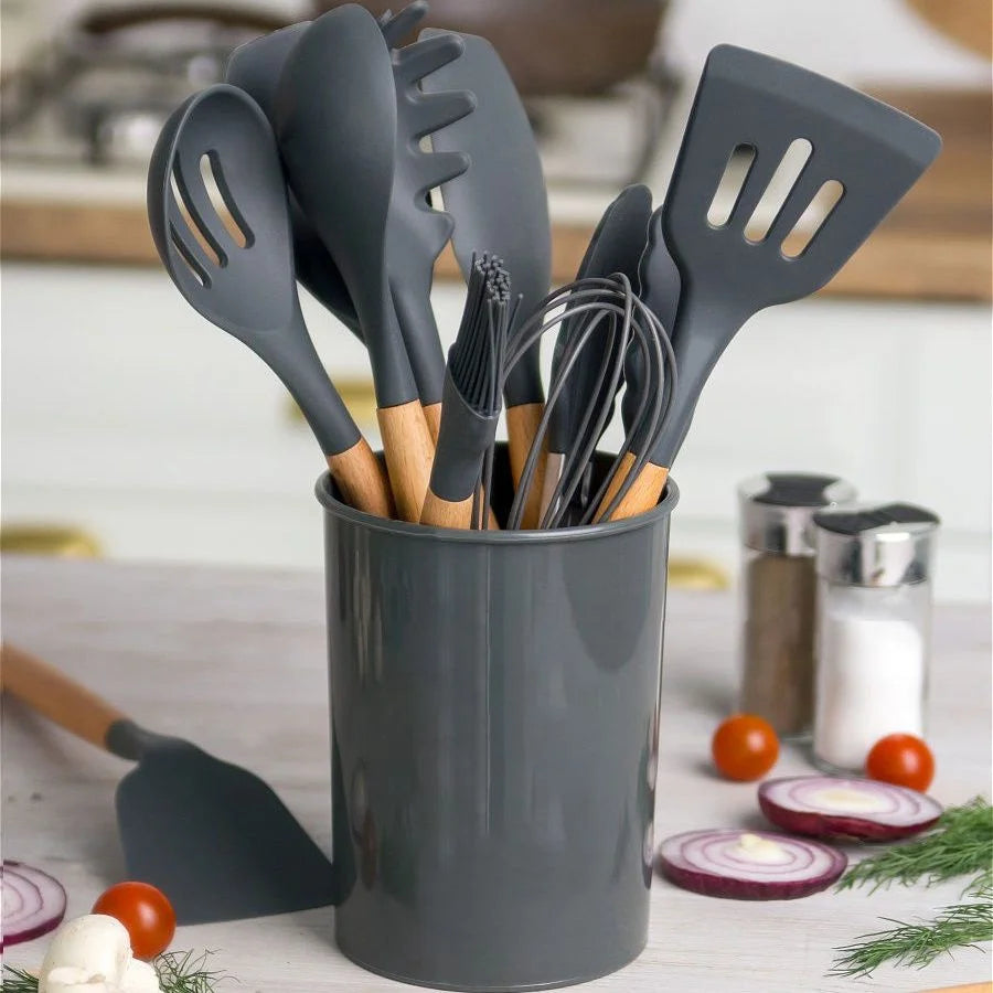 Kit de utensílios de silicone cinza com cabo de bambu, organizados dentro de um porta-utensílios na bancada da cozinha.