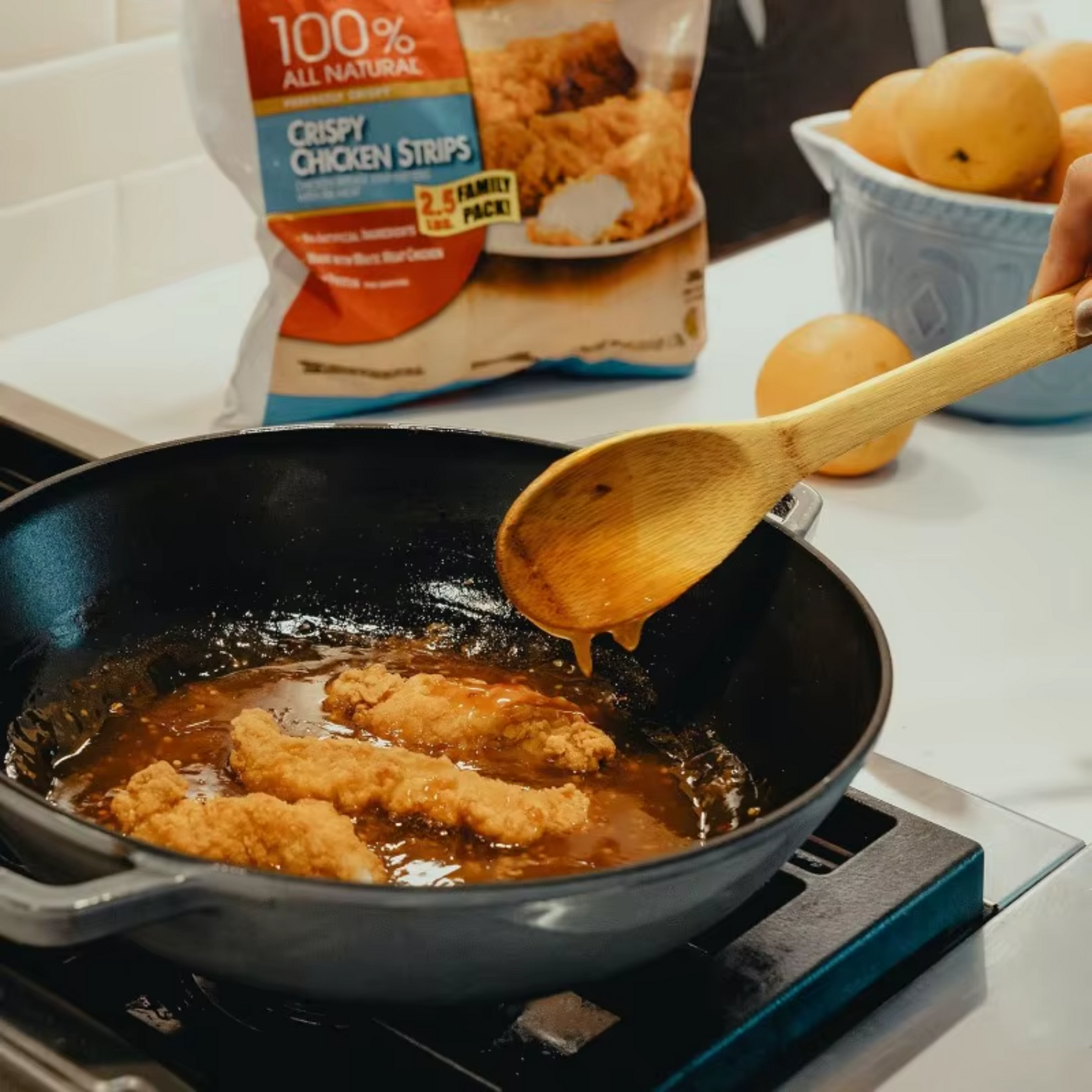 Colher de bambu mexendo alimento na frigideira durante preparo de fritura na cozinha