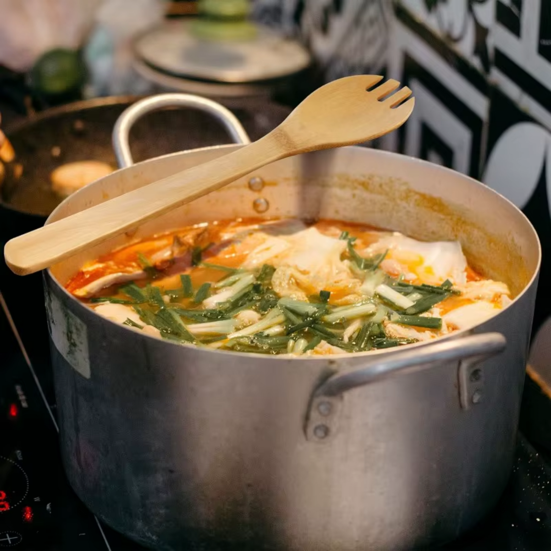 Espátula de bambu mexendo sopa de legumes em panela grande sobre fogão