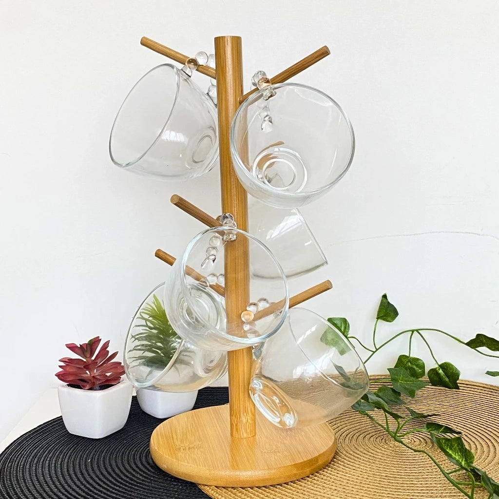Suporte de bambu organizando um par de xícaras de vidro transparente em um cantinho de café decorado com plantas.