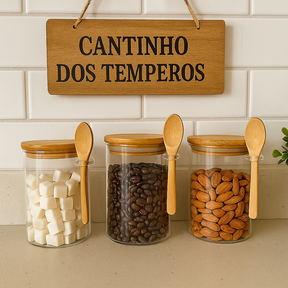 Potes de vidro com tampa de bambu e colher, armazenando açúcar, café e castanhas em cantinho de temperos.