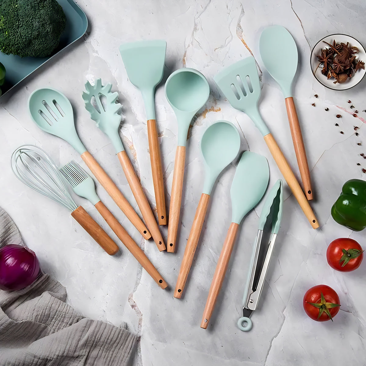 Conjunto de utensílios de cozinha verde menta com cabo de bambu, dispostos em uma superfície de mármore.