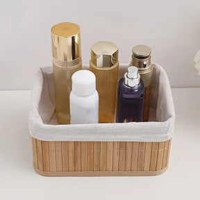 Cesto organizador de bambu com forro de tecido branco, armazenando frascos de cosméticos e perfumes.