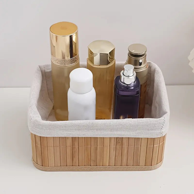 Cesto organizador de bambu com forro de tecido branco, armazenando frascos de cosméticos e perfumes.