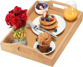 Bandeja de bambu servindo um café da manhã completo com panquecas, muffin e suco de laranja.