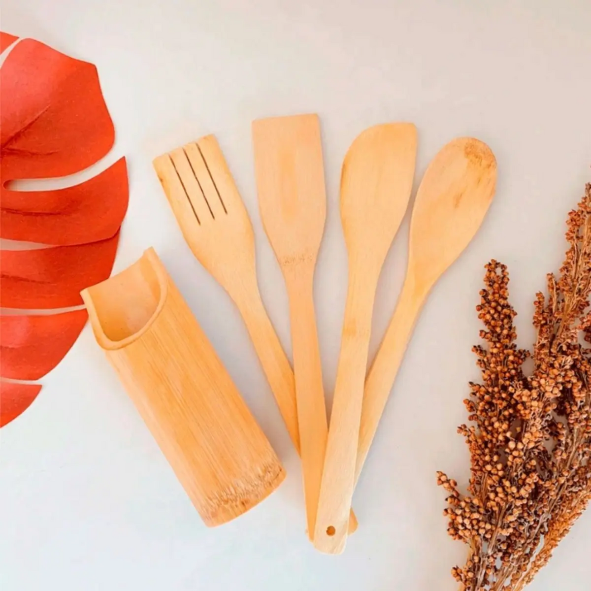 Conjunto de utensílios de bambu com colher, espátula, pegador, garfo e suporte decorativo em fundo claro