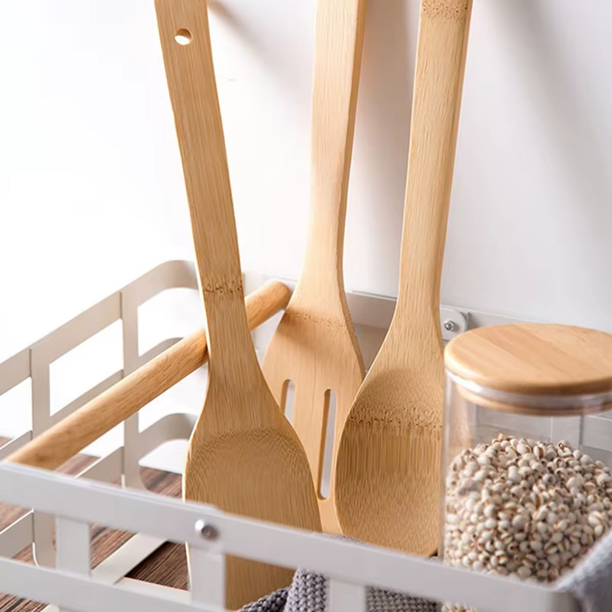Utensílios de cozinha de bambu organizados em escorredor de louças ao lado de potes de mantimentos