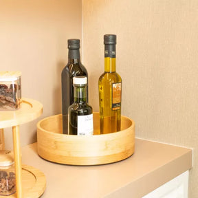 Organizador giratório de bambu com garrafas de azeite, otimizando o espaço em uma prateleira de canto da cozinha.