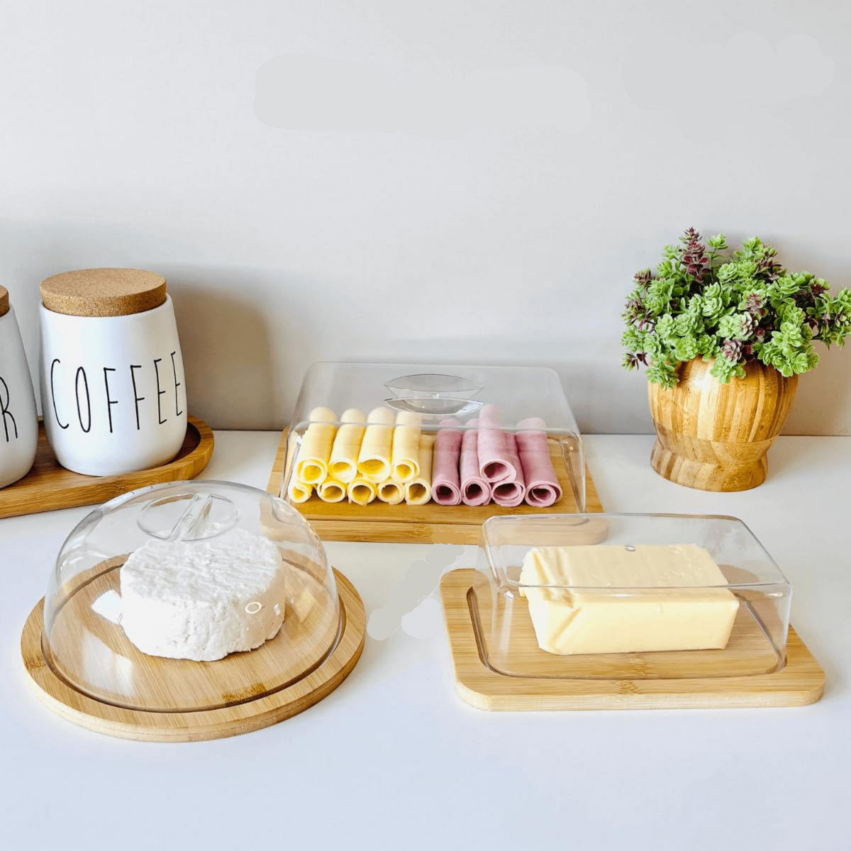 Porta frios de bambu com tampa acrílica, queijo e frios organizados sobre bancada de cozinha.