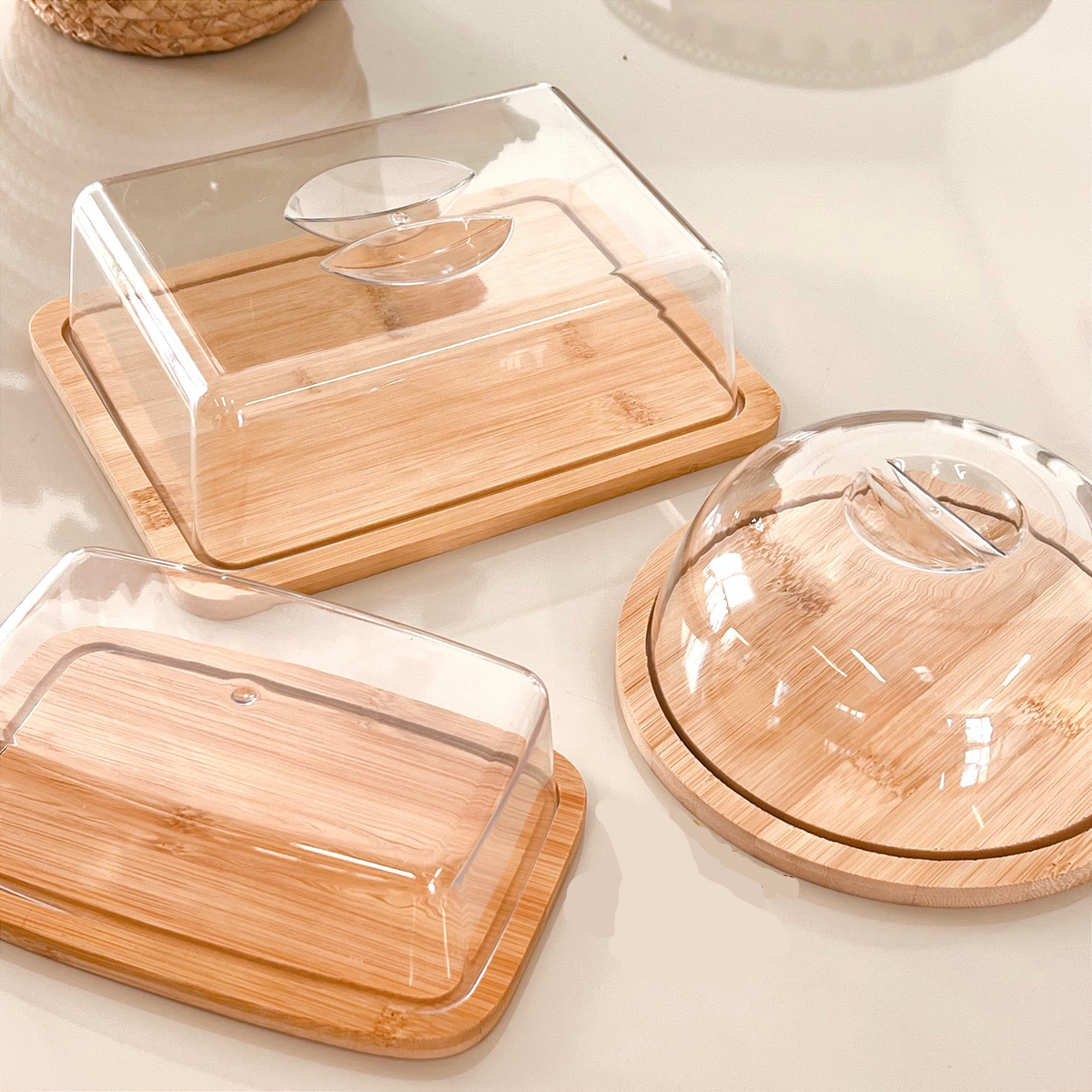 Conjunto de porta frios e queijeira de bambu com tampas acrílicas transparentes, empilhados.