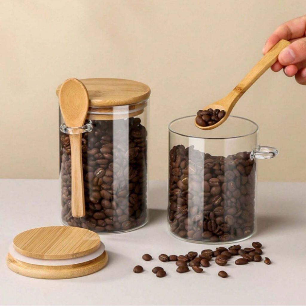 Potes de vidro com tampa de bambu e colher, grãos de café sendo servidos.