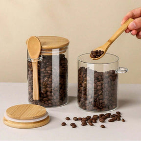 Potes de vidro com tampa de bambu e colher, grãos de café sendo servidos.