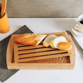Tábua migalheira de bambu com pão fatiado e ovos cozidos em uma mesa de café da manhã.