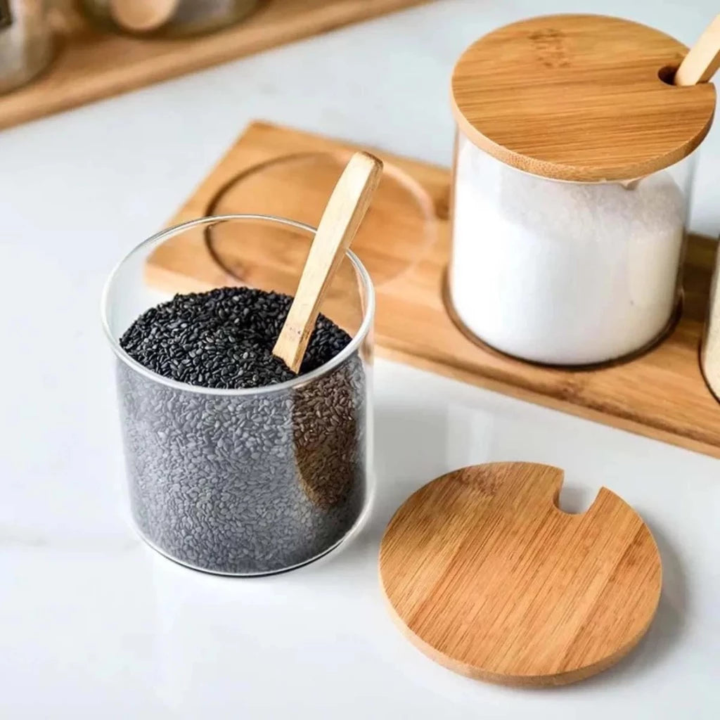 Saleiro e porta-condimentos de cerâmica com tampas e colheres de bambu, armazenando sal branco e sal negro.