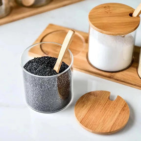 Saleiro e porta-condimentos de cerâmica com tampas e colheres de bambu, armazenando sal branco e sal negro.