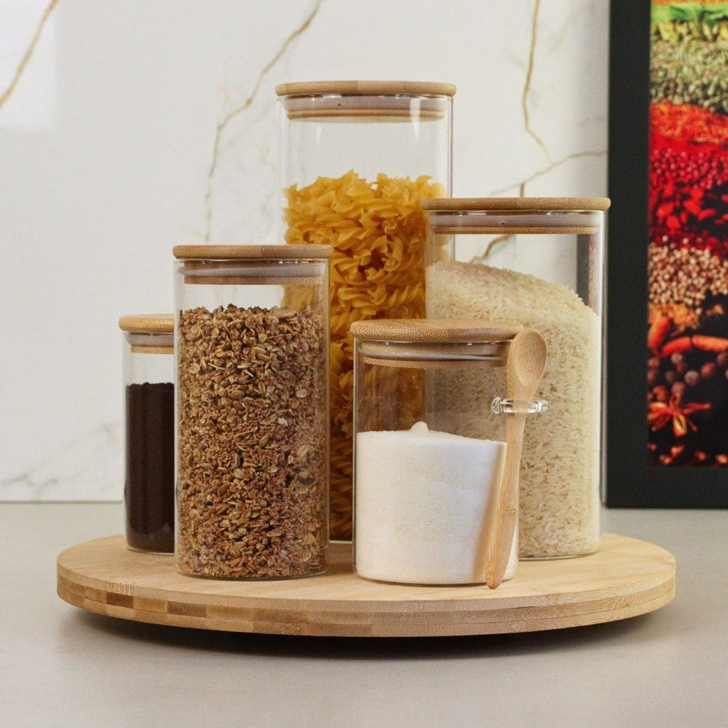 Organizador giratório de bambu com potes de vidro para mantimentos, facilitando o acesso a arroz e massas.